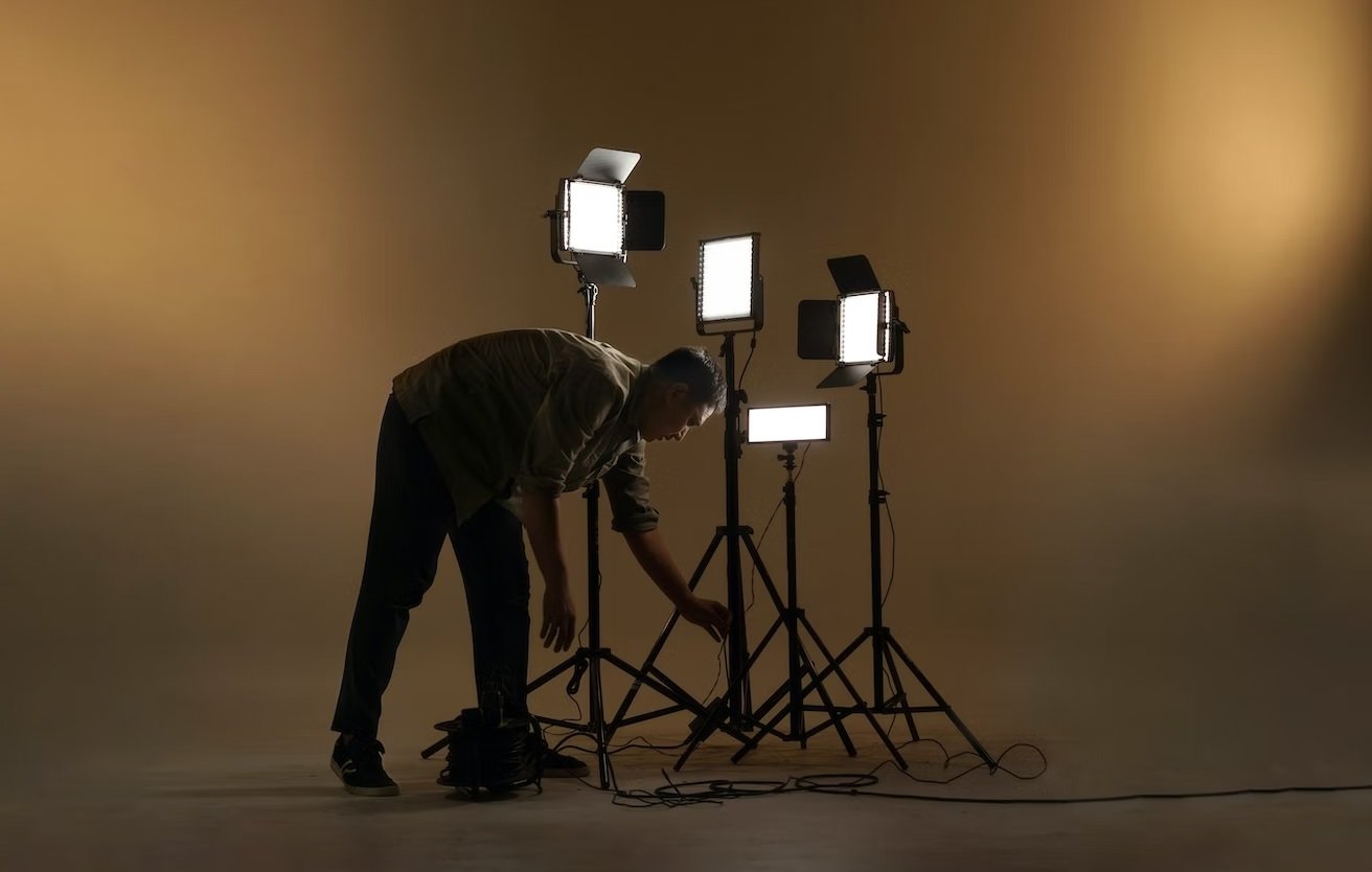 Man in a studio attending to four LED light panels on stands