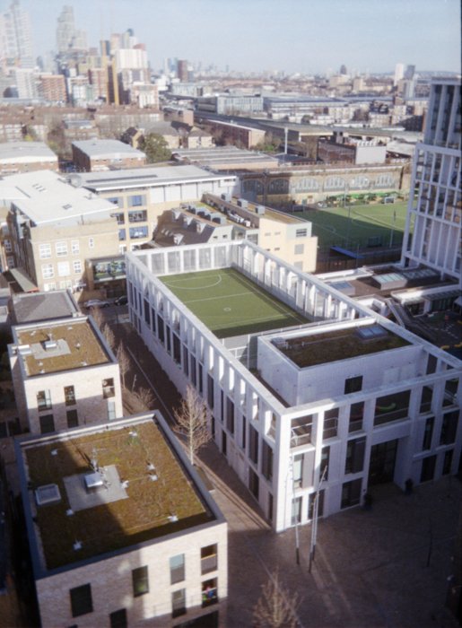 A cityscape with a football pitch in the middle of the frame