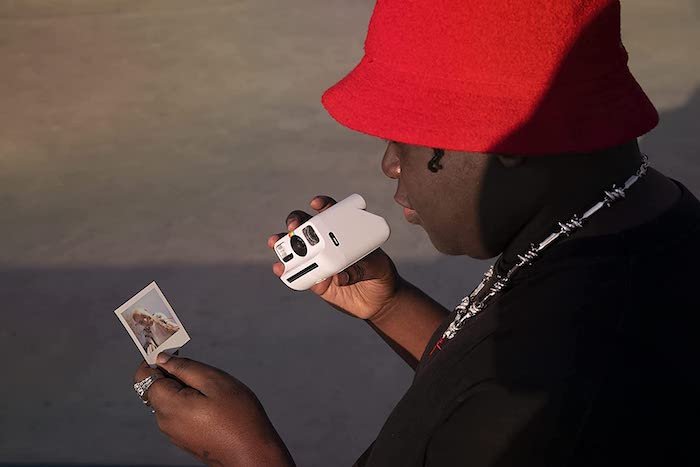 Man holding a Polaroid instant camera and print