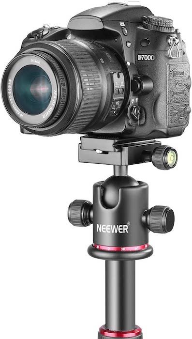 A D7000 Nikon DSLR camera and lens on top of a Neewer tripod ball head