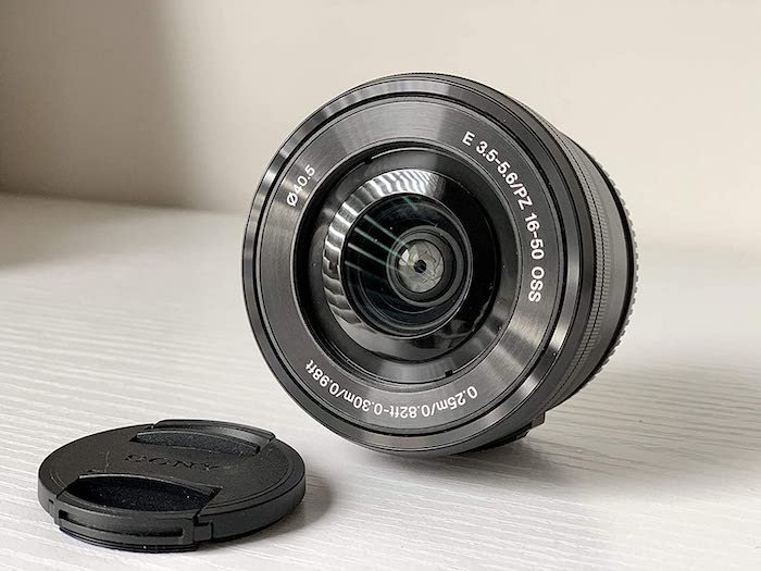 A Sony E 16-50mm f/3.5-5.6 lens for vlogging on a table with its lens cap
