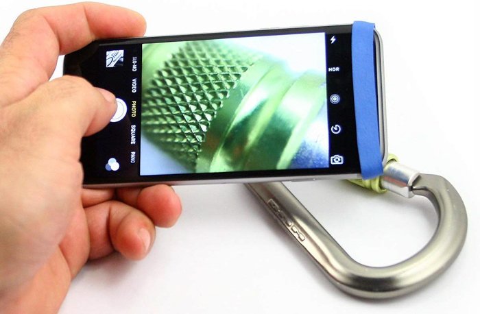 A hand holding the Easy-Macro Lens Band taking a close-up picture of a carabiner