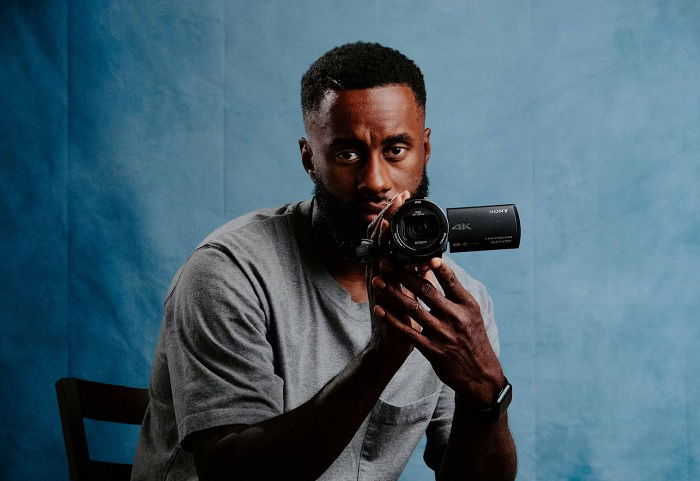 Man with a Sony camcorder in front of a blue backdrop