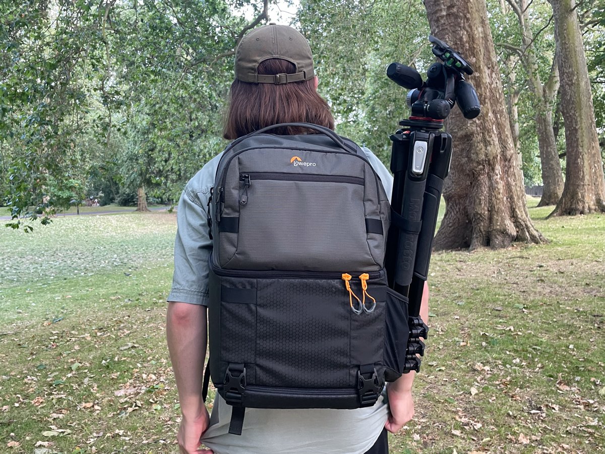 Back of the Lowepro FastPack being worn outside with a large tripod in the side pocket
