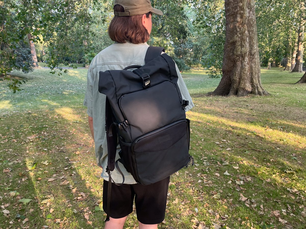 Rear view of a person wearing the Tenba DNA 16 DSLR outside in a park