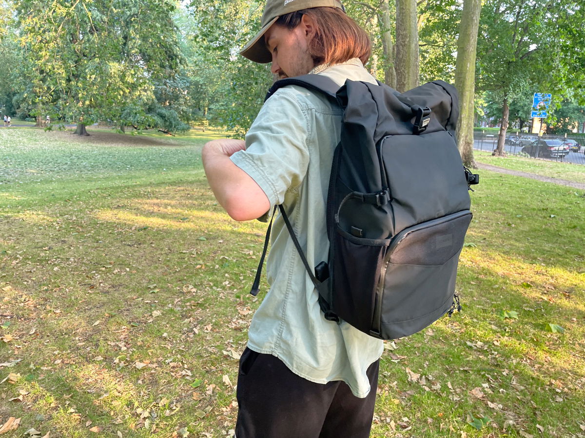 A person putting the Tenba DNA 16 DSLR outside in a park