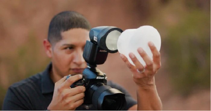 Photographer attaching a MagSphere diffuser to his flash