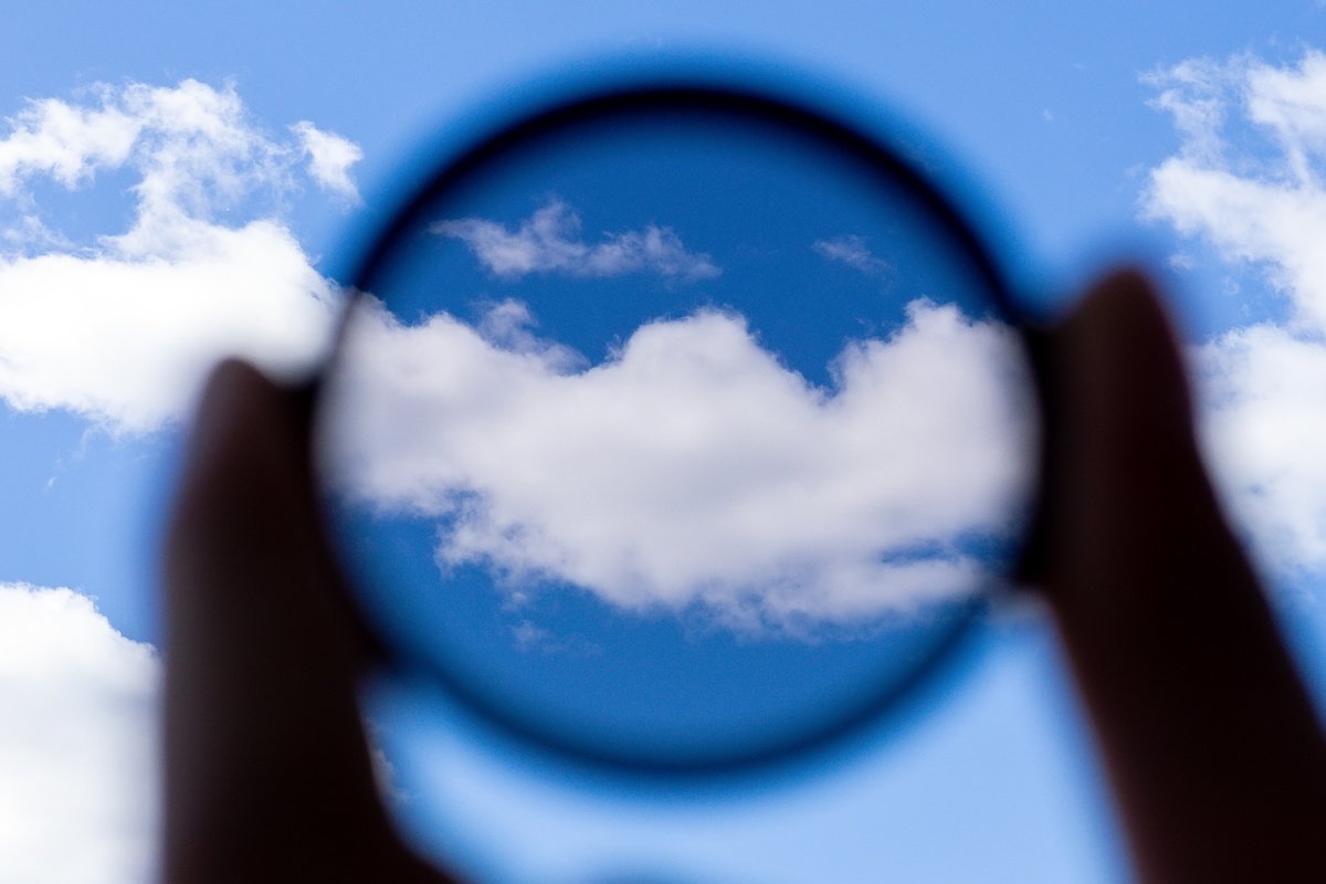A circular polarizer filter held up to a white cloud in a blue sky