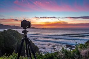 Camera on a tripod in front of a coastal sunset