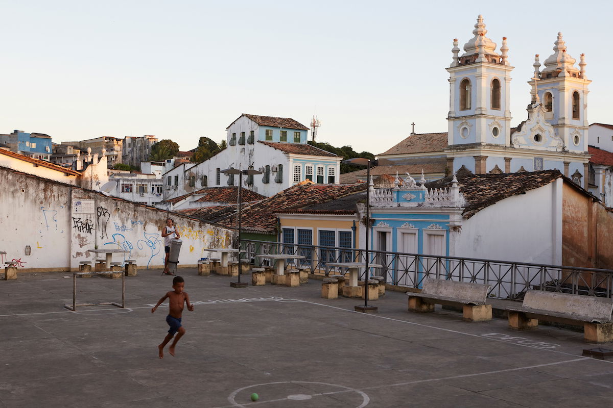 Capture One RAW image of boy playing in an urban courtyard in front of a church