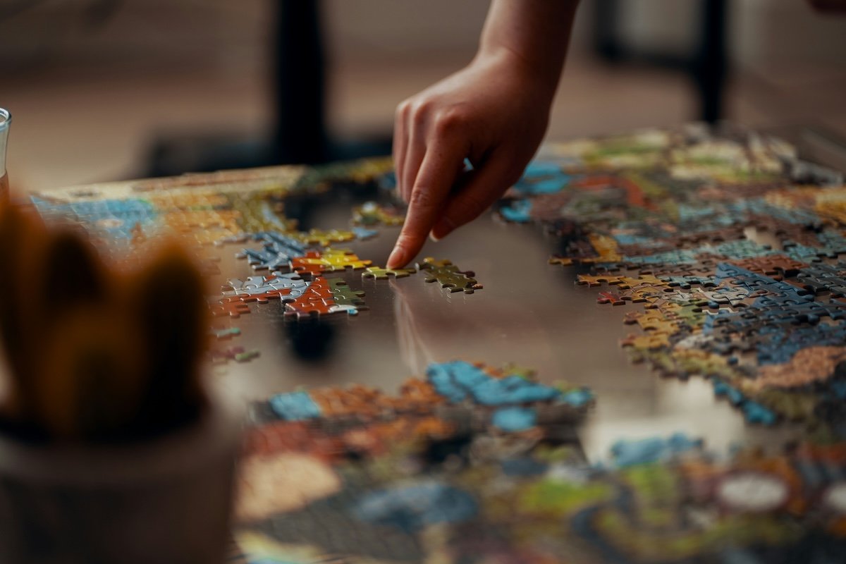 A hand moving a puzzle piece on a table shot with a wide aperture