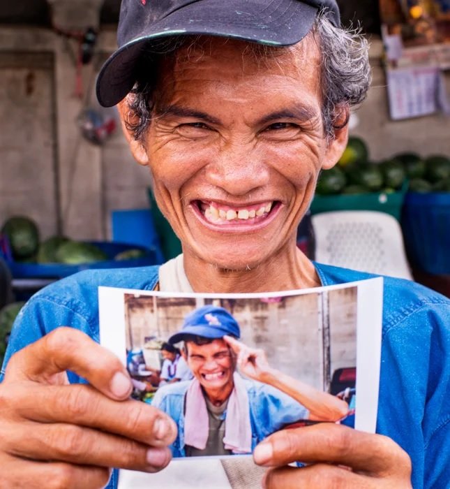 Thai man holding a photo of himself and smiling