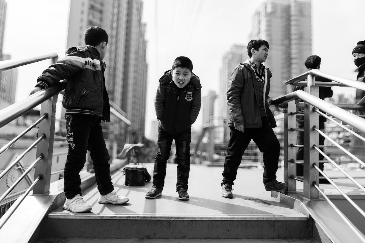 Black-and-white image of boys on a city platform with a ring bokeh lens blur in Adobe Lightroom