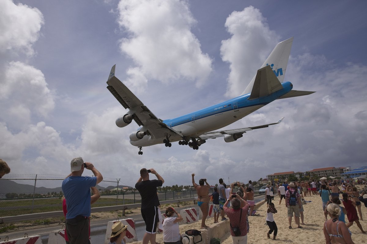Original image of a plane landing over a group of people