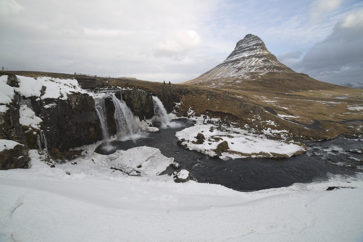 unedited image of a waterfall with a mountain in the background in the snow
