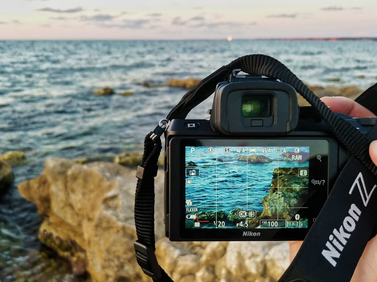 Back of a Nikon Z50 in front of a sea coastline