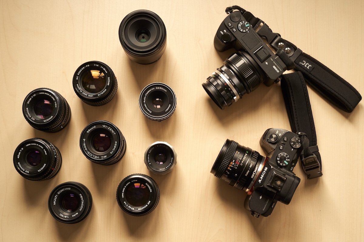 Two Sony mirrorless cameras and an assortment of lenses on a table
