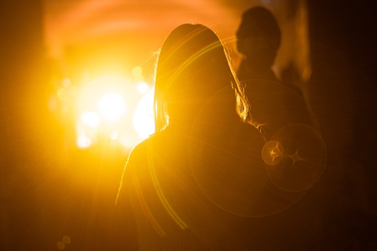 Silhouetted figures with bright yellow light and lens flare