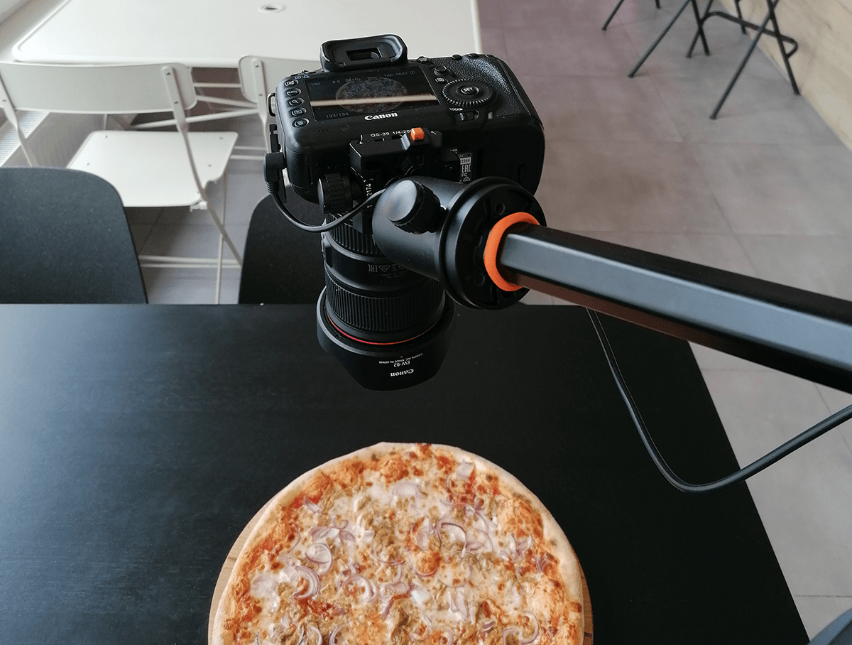 A photo showing a DSLR on a tripod taking an overhead shot of a pizza