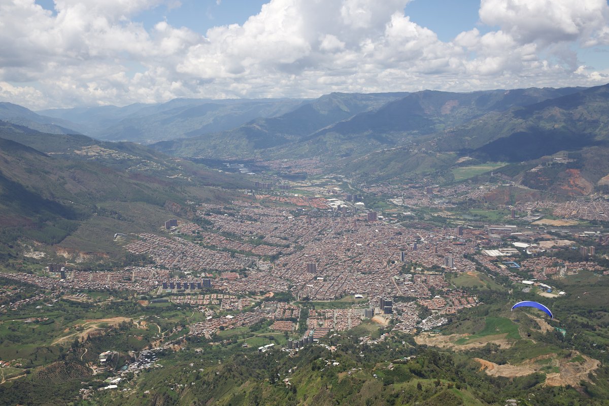photograph taken from the sky showing a city with a paraglider in the lower corner
