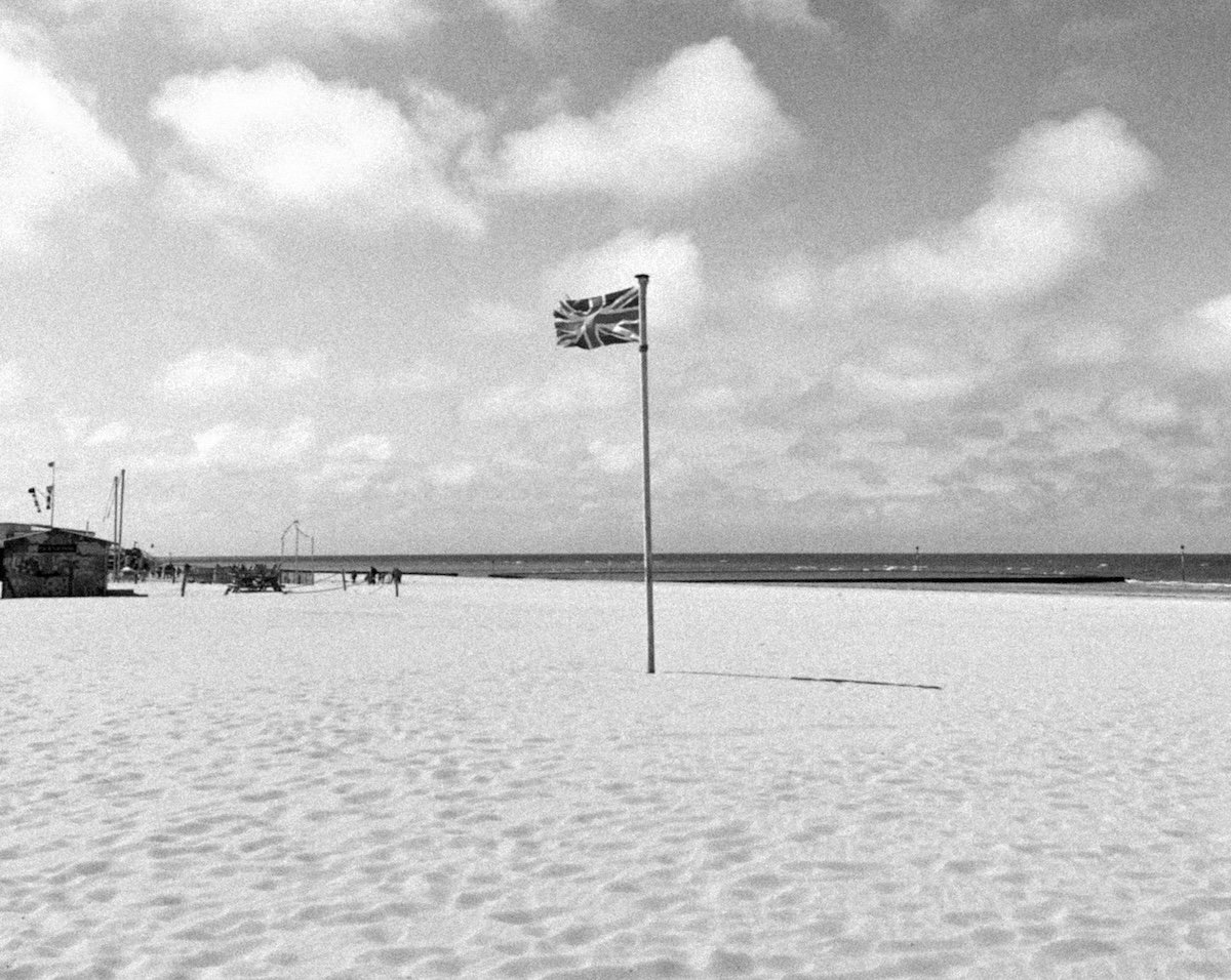 Photograph of union jack flag on a beach with large grain added