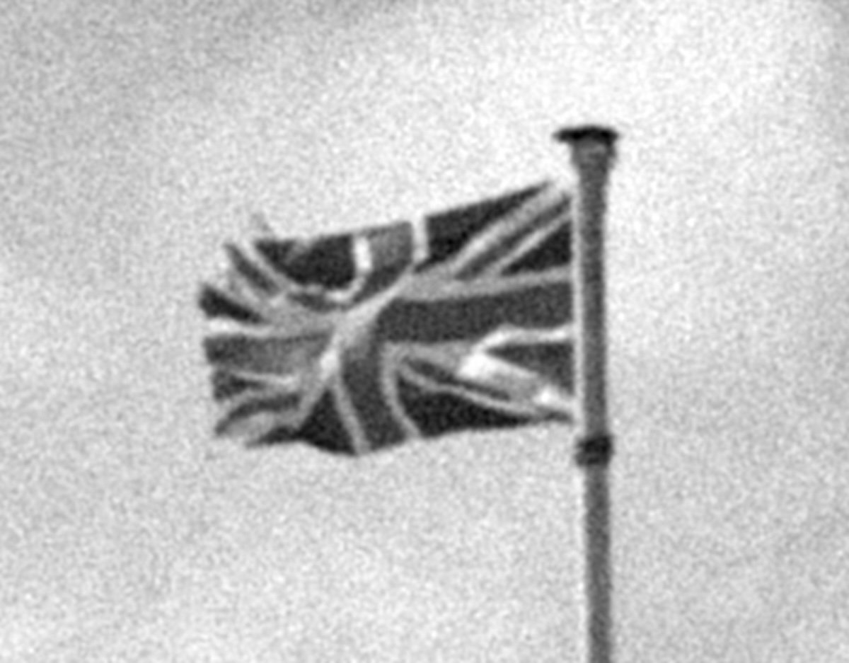 Crop of photograph of union jack flag on a beach with larger grain added