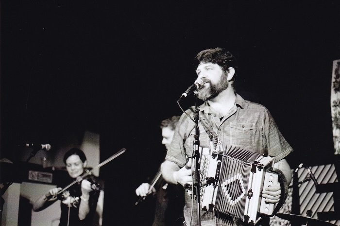 Black and white image of man playing the melodeon on stage