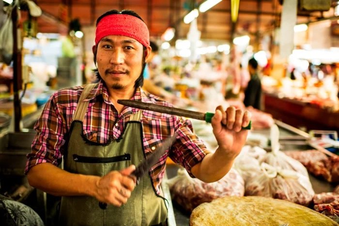 Market vendor with red headband sharpening a knife