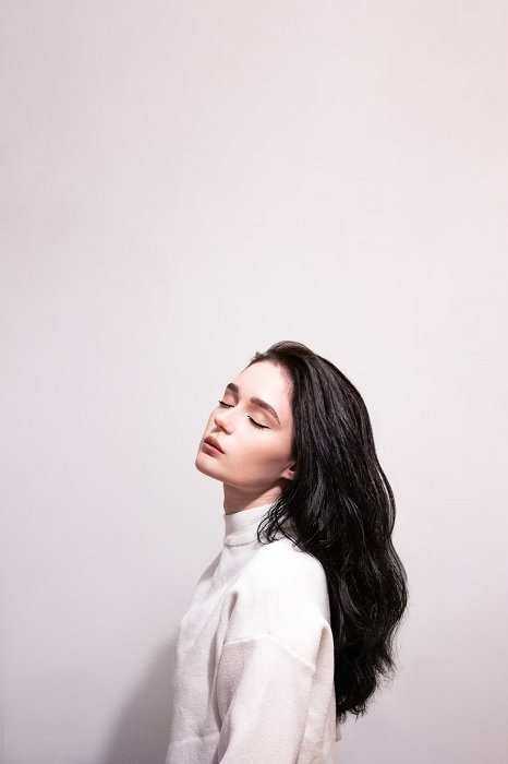 Minimalist portrait of woman with black hair against a white background
