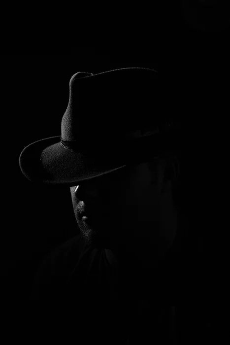 Noir-style, very dark portrait of a man in a hat