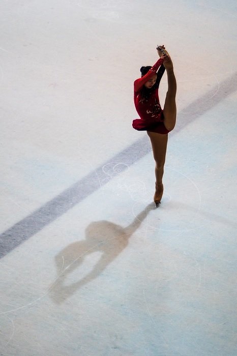 Figure skater on ice standing on one leg with the other raised vertically