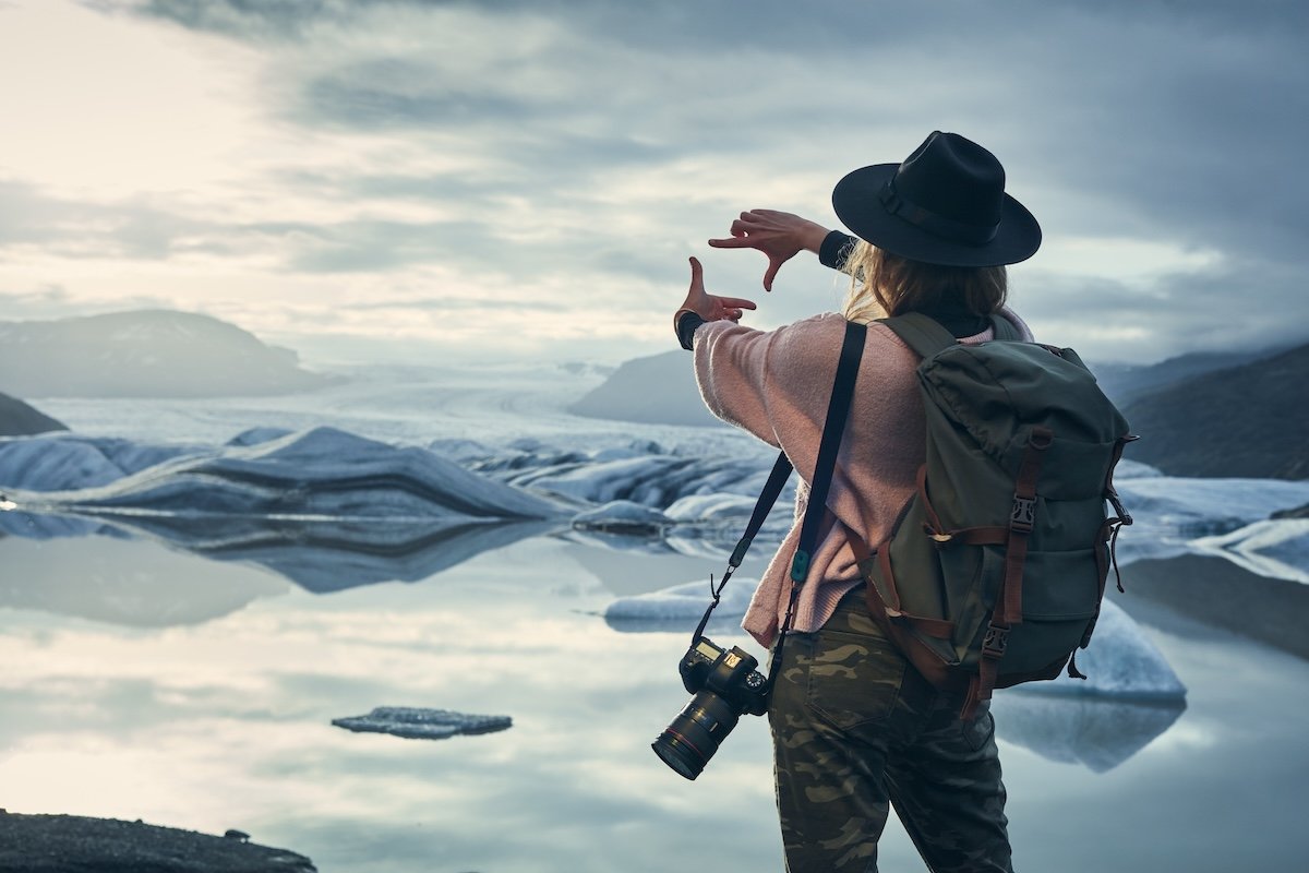 A travel photographer with a lightweight camera and bag sizing up a glacier landscape composition