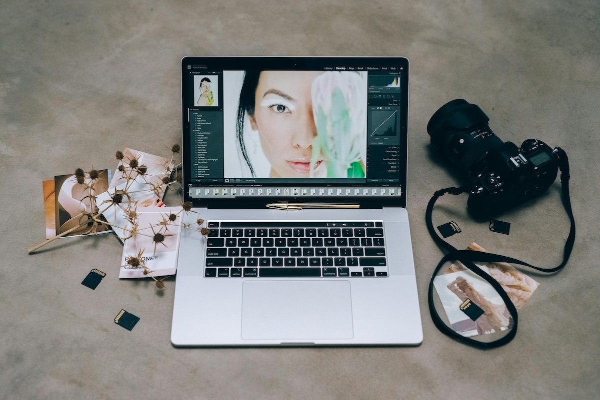photo of a camera and laptop open with lightroom showing a womans face on the screen