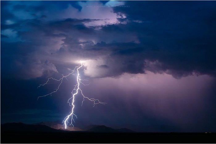 Lightning striking the ground under a dark blue stormy sky