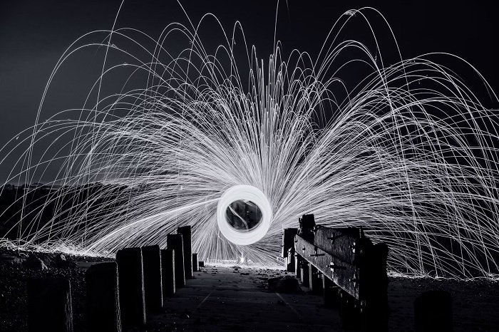 Black-and-white image of someone spinning sparkler for creative lighting ideas for photography