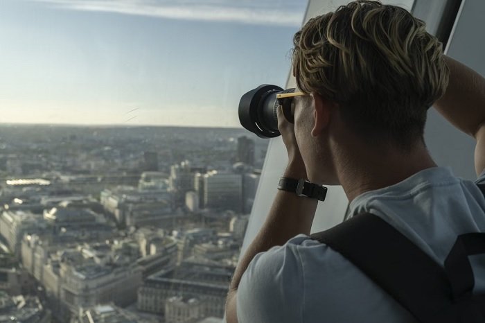 Male photographer taking a picture out of a skyscraper window in London