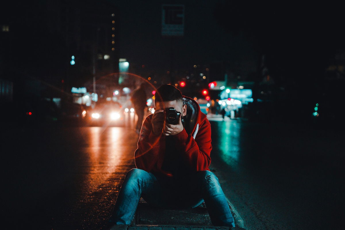 man photographing in middle of the road at night