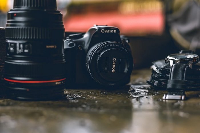 Canon Camera on a surface next to a Canon lens
