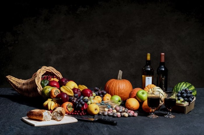 Still life of fruit, wine and bread arranged on a dark table