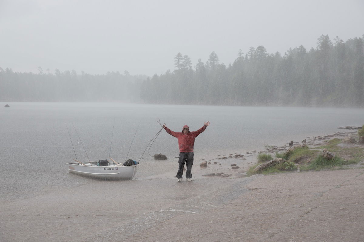 man standing next to a fishing boat in the rain with reduced dehaze