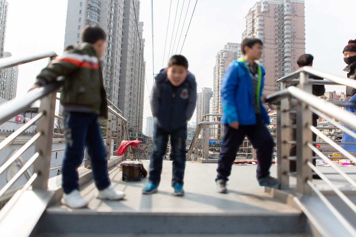 photograph of three boys on a bridge blurred with buildings in the background in focus
