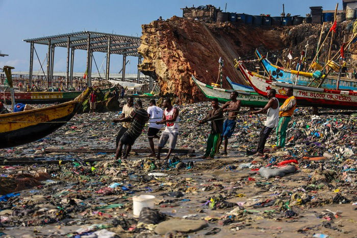 Men hauling a boat onto a dirty beach