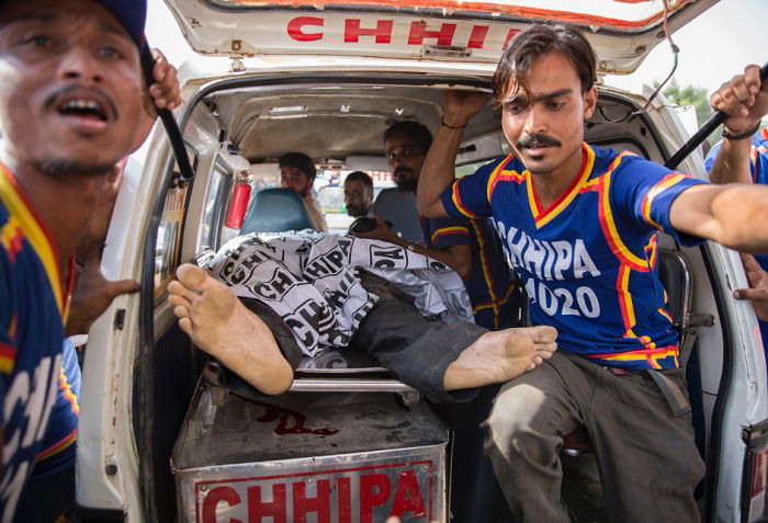 Two men carrying person out of a small ambulance