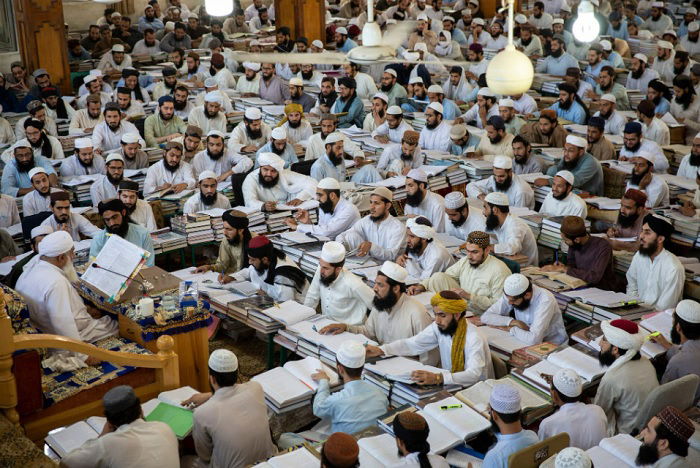 Loads of Muslim men sitting with books