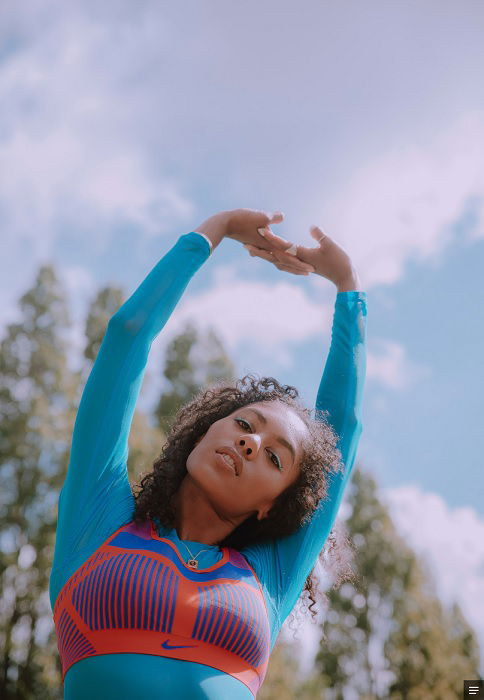 Woman in running gear stretching arms over head