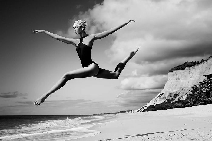 Woman leaping with legs outstretched on a beach