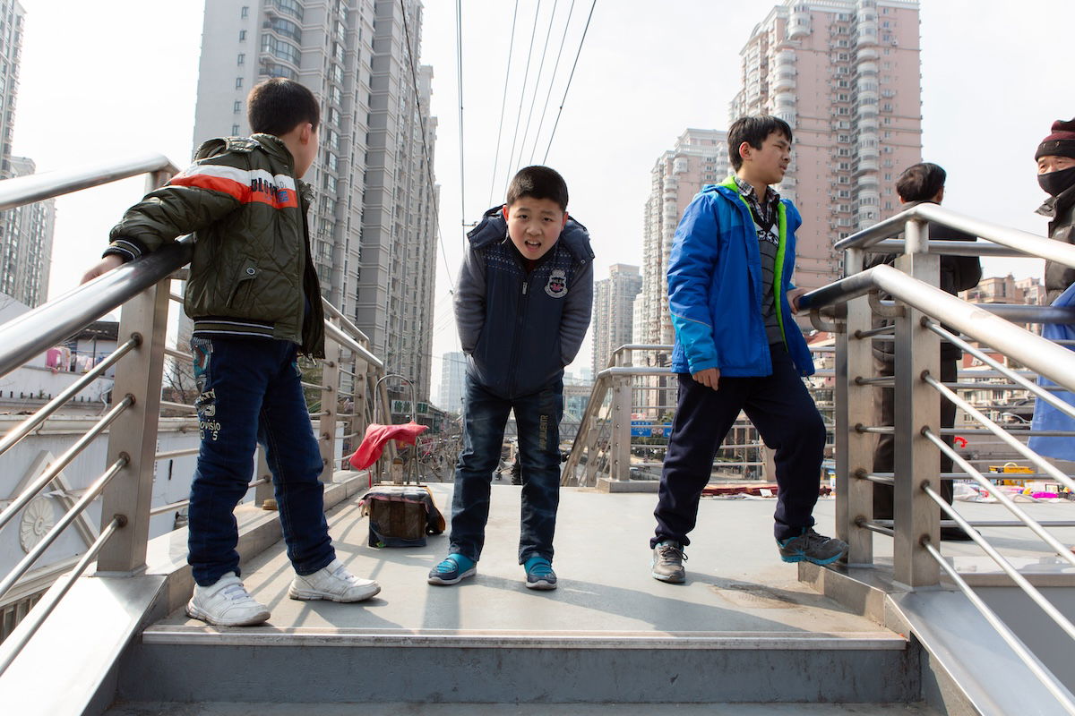 photograph of boys on a bridge in a city with lens corrections enabled in lightroom