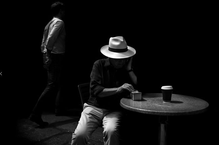 Man in hat sat at table with a coffee cup