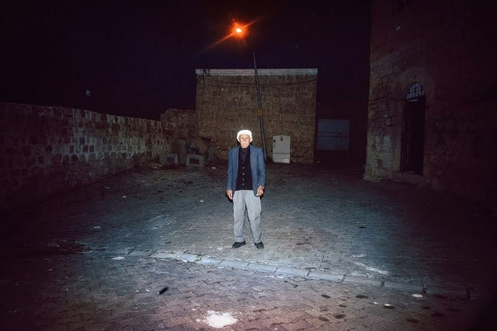 Photo of old man standing in a yard at night
