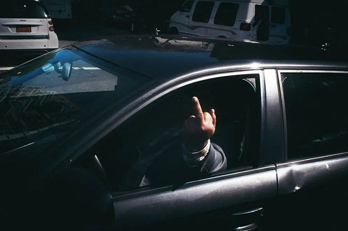 Man in car giving the finger to the photographer